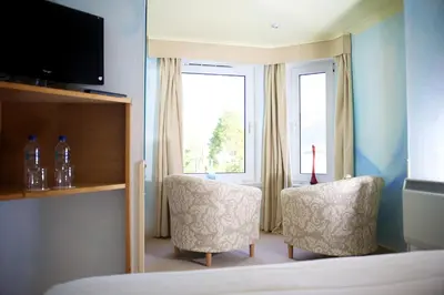 a hotel room with two chairs and a window at The Lodge on the Loch by OYO in Onich