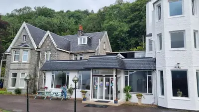 a house with a conservatory in front of it at The Lodge on the Loch by OYO in Onich
