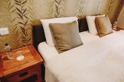 two beds in a room with a night stand and a table at The Lodge on the Loch by OYO in Onich