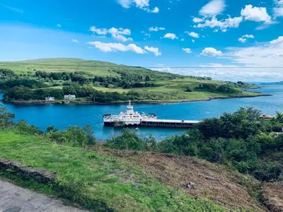 a ferry in a lake with hills in the background at White Watch in Lochaline
