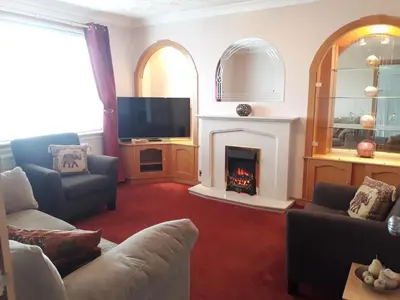 a living room with a fireplace and a tv at Hilltop House in Airdrie