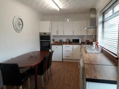 a kitchen with white cabinets and a wooden table at Hilltop House in Airdrie