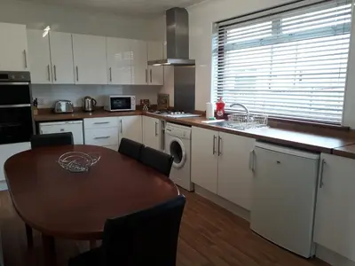 a kitchen with a wooden table and a table and a dining room at Hilltop House in Airdrie