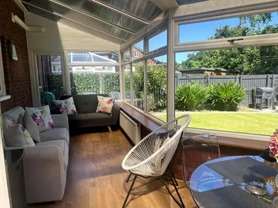 a screened in porch with a couch and a glass table at Meadow House- Driveway Parking and Fireplace in East Kilbride
