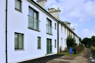 a row of white houses with windows on a street at Red Watch Apartment in Oban