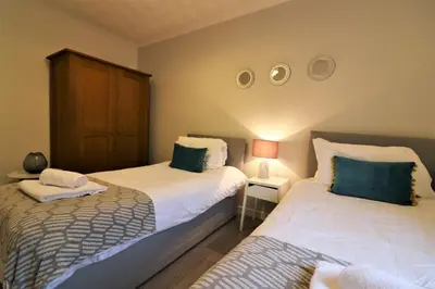 a bedroom with two beds and a table with a lamp at Signature - Bruce Terrace Lower in High Blantyre