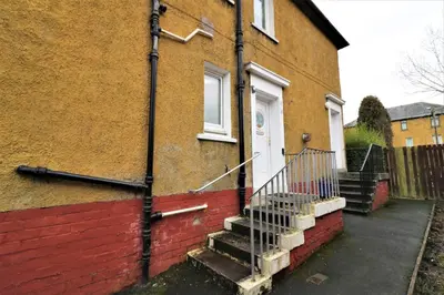a brick house with a white door and stairs at Signature - Bruce Terrace Lower in High Blantyre