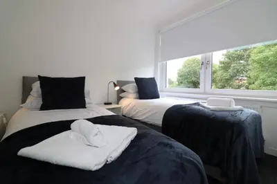 two beds with towels on them in a room with a window at Signature - New View Place in Bellshill