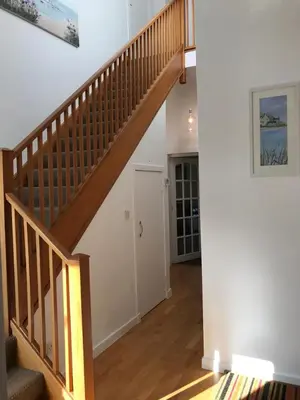 a wooden staircase in a living room with a door at Arran Ferry Apartment in Ardrossan