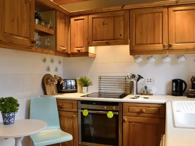 a kitchen with wooden cabinets and a stove top oven at Haagwood Cottage in Cretshengan