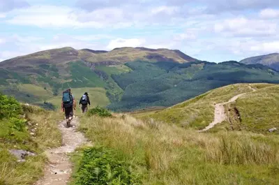 two people riding bikes down a trail on a hill at A Fairytale Highland Cottage in Aberfeldy