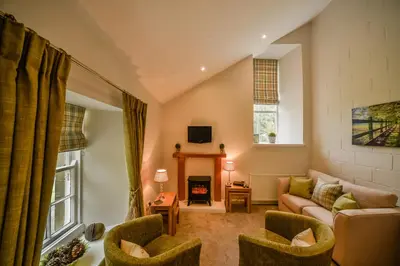 a living room with a couch and a fireplace at Blairquhan Cottages in Maybole