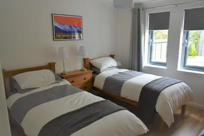 two beds in a room with two windows at Hawthorn Cottage in Glencoe