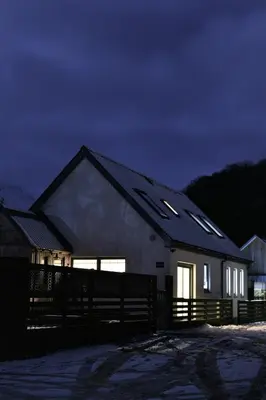 a house with lights on the side of it at night at Hawthorn Cottage in Glencoe
