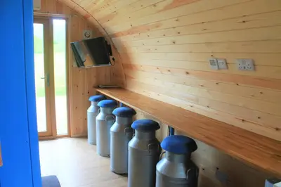 a room with a wooden wall with a row of metal cylinders at Cairnfold Cabins in Kilsyth
