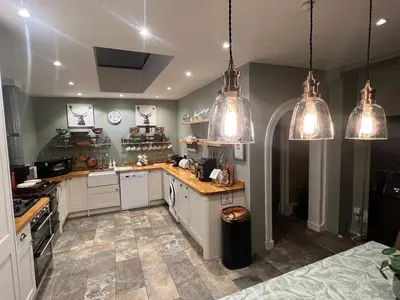 a kitchen with white cabinets and pendant lights at Rhumhor House in Carrick