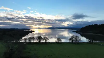 a view of a river with trees in a field at Coachmans Bothy - 50m from the beach in Port Appin