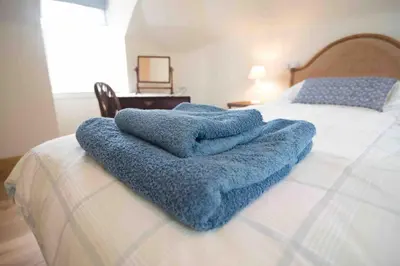 a blue blanket sitting on top of a bed at Coachmans Bothy - 50m from the beach in Port Appin