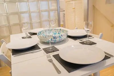 a table with white plates and wine glasses on it at 2BR Grassmarket Apartment with Castle View in Edinburgh