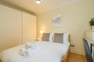 a bedroom with a white bed with a stuffed animal on it at 2BR Grassmarket Apartment with Castle View in Edinburgh