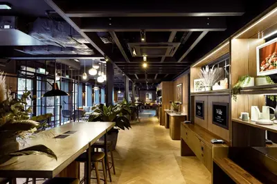 a restaurant with a long corridor with tables and plants at Wilde Aparthotels Edinburgh Grassmarket in Edinburgh