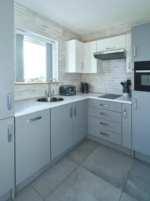 a kitchen with white cabinets and a sink and a window at Blue Watch in Lochaline