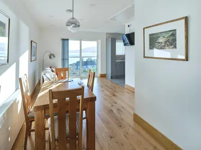 a dining room and kitchen with a wooden table and chairs at Blue Watch in Lochaline
