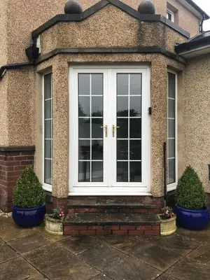 a white door on a house with two plants at The Neuk in Uphall