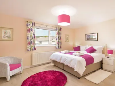 a bedroom with a large bed and a pink rug at Westburn in Comrie