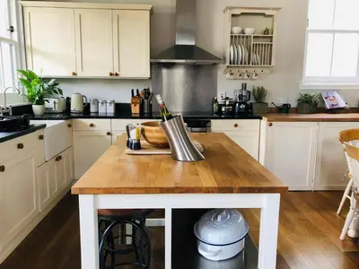 a kitchen with white cabinets and a wooden table at Chefs cottage in Kenmore