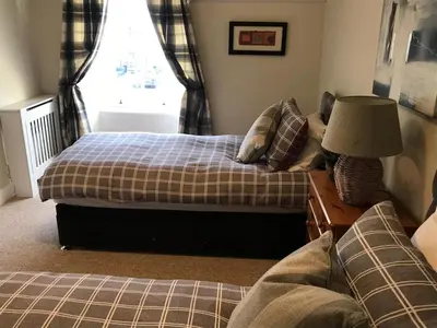 a bedroom with two beds and a lamp on a table at Chefs cottage in Kenmore