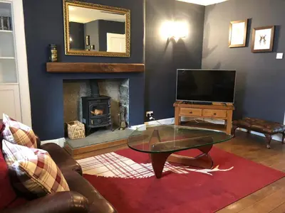 a living room with a glass coffee table and a fireplace at Chefs cottage in Kenmore