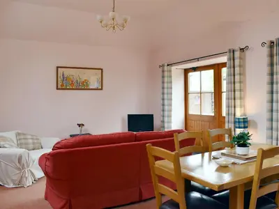 a living room with a red couch and a table at The Cottage At Cauldcoats in Linlithgow