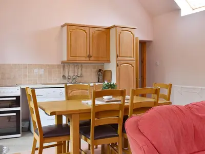 a kitchen with a wooden table and chairs and a table and a kitchen at The Cottage At Cauldcoats in Linlithgow