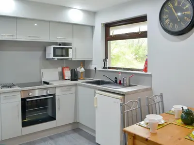 a kitchen with white cabinets and a clock on the wall at Puffin - Kerrera in Lerags