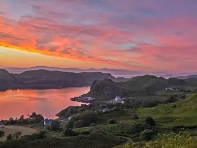a sunset over a body of water with mountains at Puffin - Kerrera in Lerags
