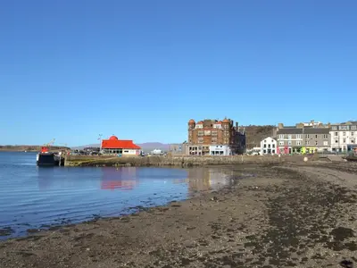 a view of a beach with buildings in the background at Puffin - Kerrera in Lerags