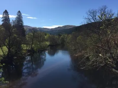 a view of a river with trees on the side at Sir Andrew Murray House in Strathyre