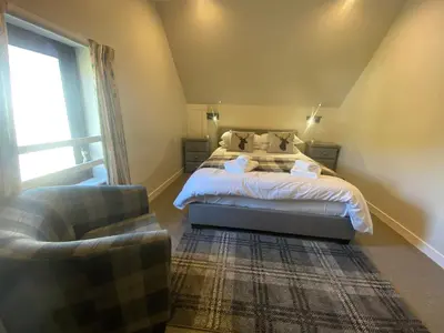 a bedroom with a bed and a chair and a window at Puffin - Bach in Lerags