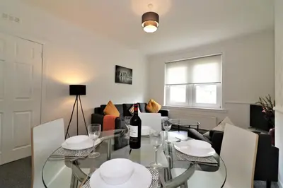a dining room with a glass table with a bottle of wine at Signature - Shawburn House in Hamilton
