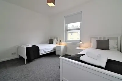 a white room with two beds and a window at Signature - Shawburn House in Hamilton