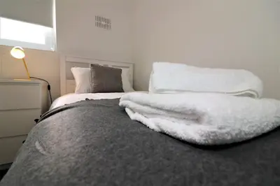 a bedroom with a bed with a white blanket on it at Signature - Belhaven House in Hamilton