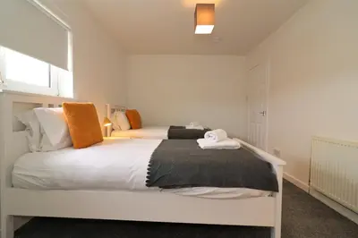 a bedroom with a bed with white sheets and orange pillows at Signature - Belhaven House in Hamilton