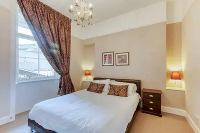 a bedroom with a bed and a window with a chandelier at West Port - 2BR in the heart of the old town just off the Grassmarket in Edinburgh
