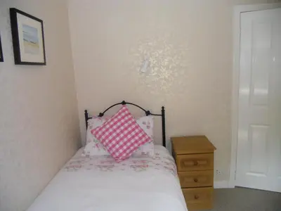 a bedroom with a bed with a pink and white pillow at Ormidale Hotel in Brodick