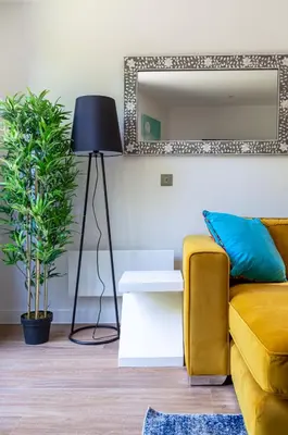 a living room with a yellow couch and a mirror at Castle View Luxury 1 Bed Apartment in Edinburgh
