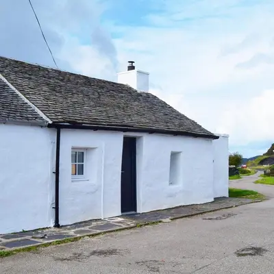a white house with a black door on a street at Number 10, Isle of Luing in Cullipool