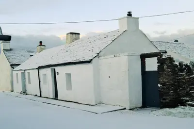 an old white building with a roof in the snow at Number 10, Isle of Luing in Cullipool