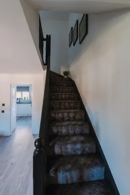 a staircase in a house with a rug at Emirates ApartHOUSE in Glasgow