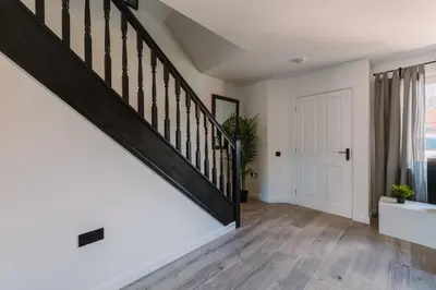 a staircase in a home with white walls and wood floors at Emirates ApartHOUSE in Glasgow